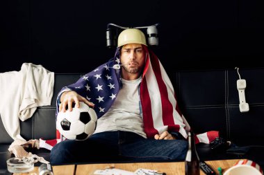 kask bira içip futbol omuzlarında Amerikan bayrağı ile otururken tutan giyen adam