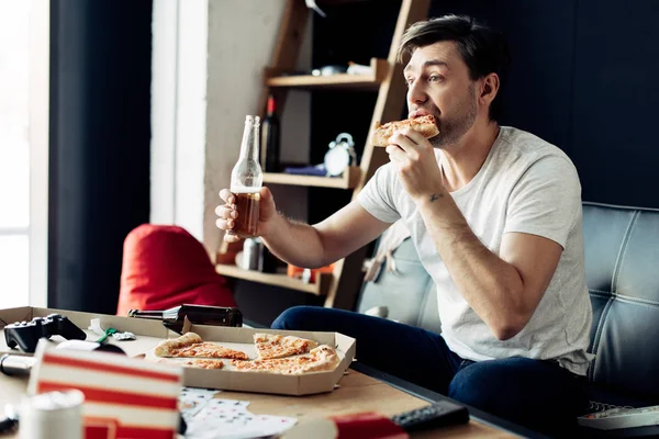 Uomo Mangiare Pizza Mentre Tiene Bottiglia Soggiorno — Foto Stock