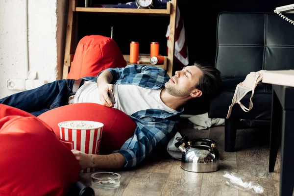 Pria Tampan Berbaring Kantong Kacang Dan Memegang Kotak Popcorn — Stok Foto