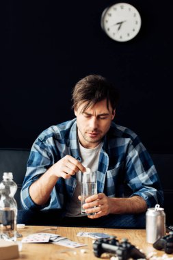 tired man suffering from hangover holding aspirin and glass of water in hands clipart
