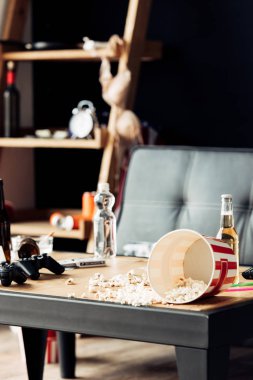 selective focus of popcorn near bottles with beer on coffee table clipart