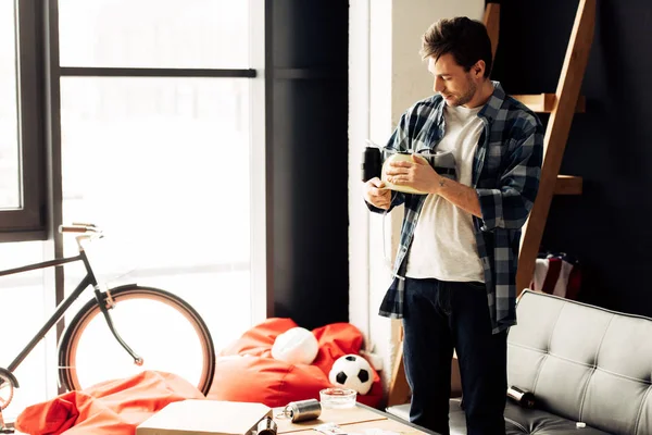 Man Holding Beer Helmet Hands Standing Messy Living Room — Stock Photo, Image