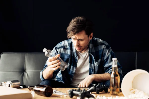 Handsome Man Suffering Hangover Looking Empty Bottle While Sitting Sofa — Stock Photo, Image