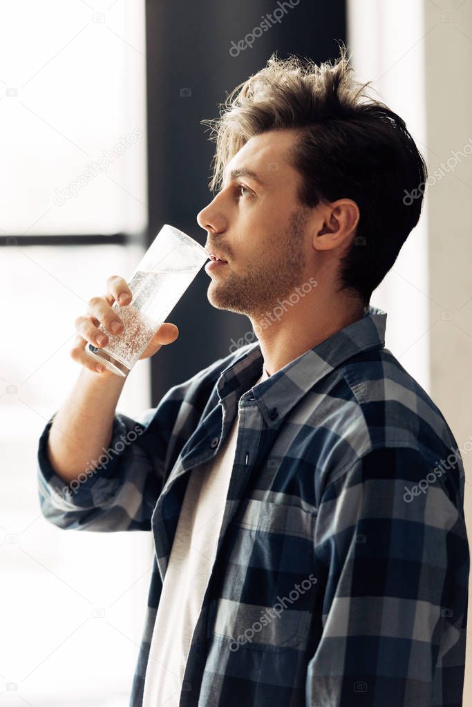 handsome man holding glass and drinking water after party
