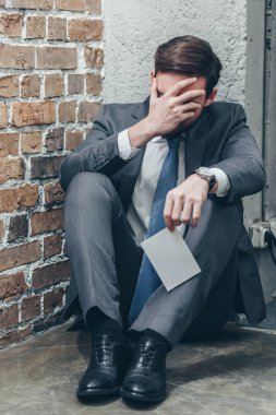 katta oturan, fotoğraf holding ve crying on kahverengi dokulu arka plan Oda, gri takım elbiseli adam bozukluğu kavramı kederli