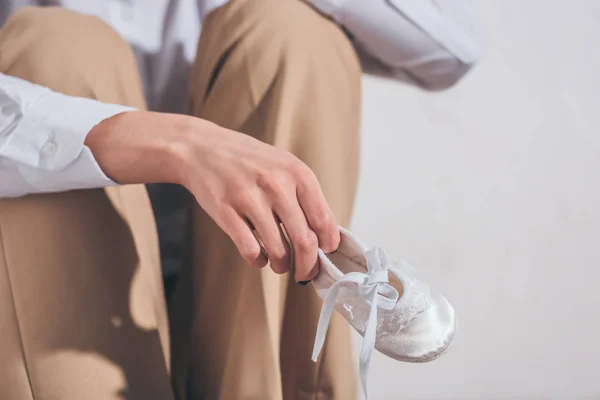 Vista Cortada Mulher Calças Bege Segurando Sapato Bebê Sentado Fundo — Fotografia de Stock