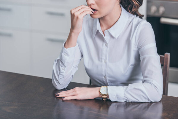 обрезанный вид грустной женщины в белой блузке, сидящей за столом на кухне, скорбящее расстройство концепции
