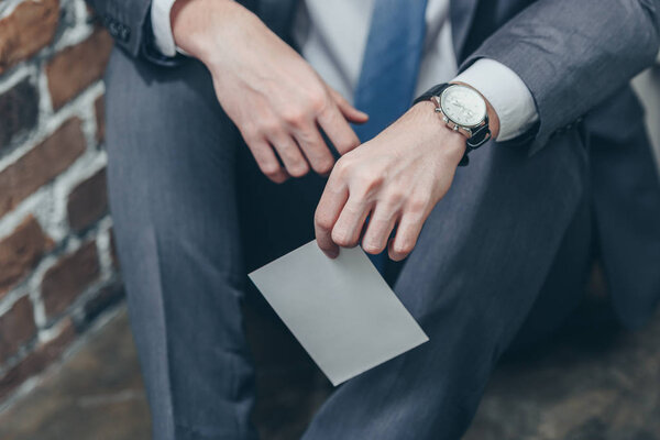 обрезанный вид человека, сидящего на полу и держащего фотографию, концепция расстройства скорби
