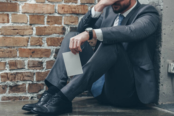 обрезанный вид человека, сидящего в углу и держащего фотографию на коричневом текстурированном фоне в комнате, скорбящее расстройство концепции
