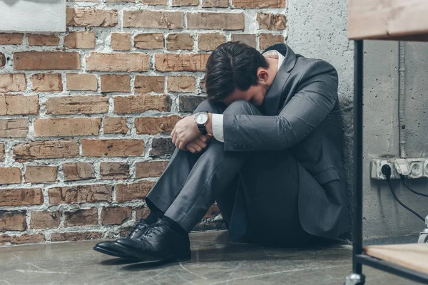 Sad Man Gray Suit Sitting Floor Hugging Knees Brown Textured — Stock Photo, Image