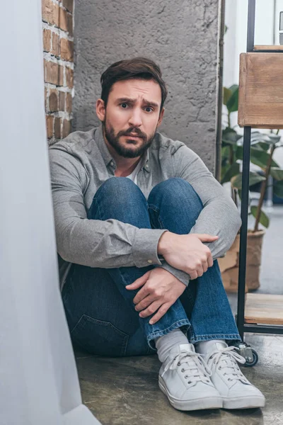 Sad Man Sitting Corner Hugging Knees Textured Background Room Grieving — Stock Photo, Image