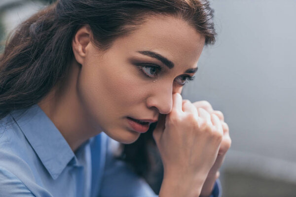 portrait of sad crying woman in blue blouse in room, grieving disorder concept