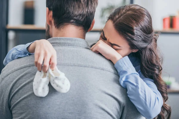 Woman Crying Hugging Man Holding Baby Socks Home Grieving Disorder — Stock Photo, Image