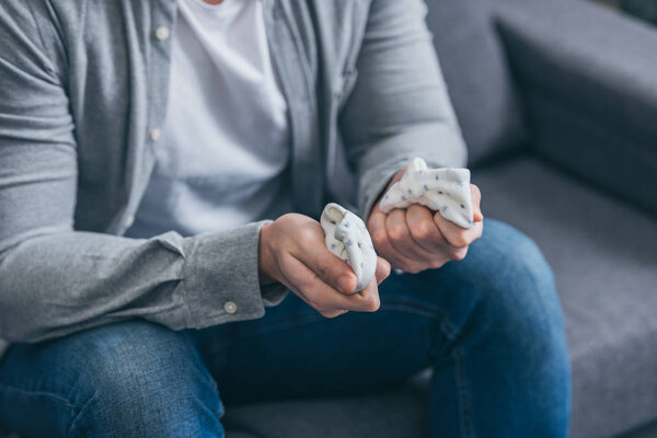 обрезанный вид человека, сидящего на диване и держащего детские носки дома, скорбящее расстройство концепции
