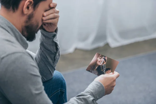 裁剪视图悲伤的男人坐在家里拿着照片与妇女 悲伤的混乱概念 — 图库照片