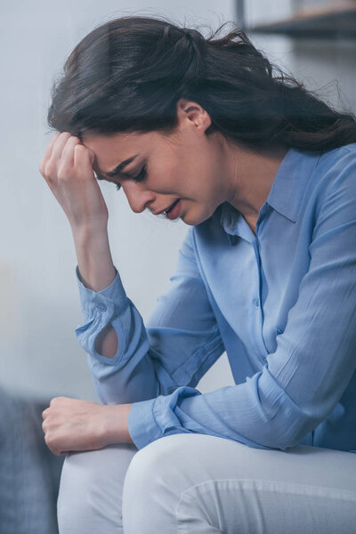upset woman having headache, grieving and crying at home