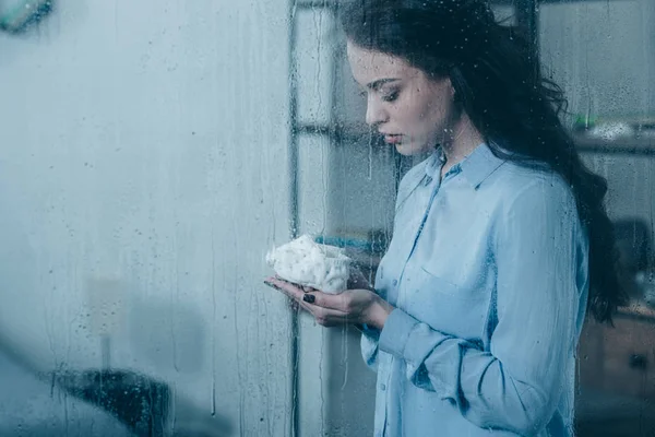 Grieving Mother Holding Baby Shoes Window Raindrops Copy Space — Stock Photo, Image