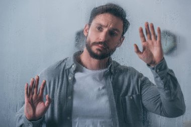 yağmur damlaları ile pencere dokunmaktan ve uzağa bakarak üzgün yakışıklı