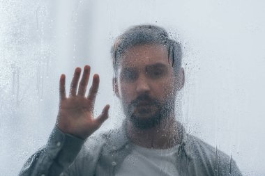 selective focus of raindrops on window with upset man on background clipart
