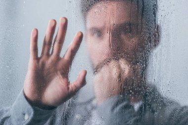 el ile ağız kapsayan ve yağmur damlaları ile pencere dokunmadan üzgün adam