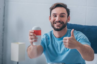 Cenaze semaver holding, kameraya bakıyor ve başparmak işaret yukarıya gösterilen gülümseyen adam