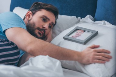 yatakta yatan ve kadın evde yastık üzerinde resim yakınındaki kederli adam