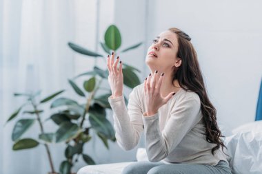 frustrated woman gesturing with hands and grieving at home clipart