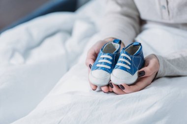 Kırpılan görünümünü yatakta yatan Bebek Patiği tutan kadın