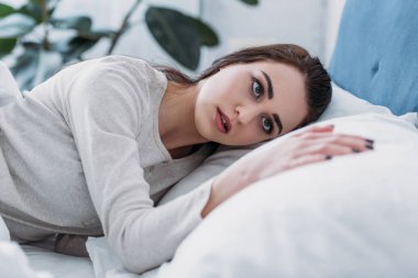 seçici odak güzel üzgün kadının evde yatakta yatarken pijama