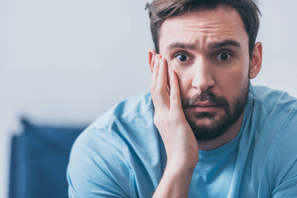 красивый испуганный мужчина с рукой на голове смотрит в камеру дома с копировальным пространством
