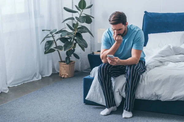 Grieving Man Sitting Bed Covering Mouth Hand Using Smartphone Home — Stock Photo, Image