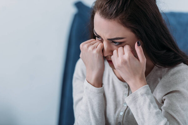 selective focus of depressed woman crying and wiping tears with copy space
