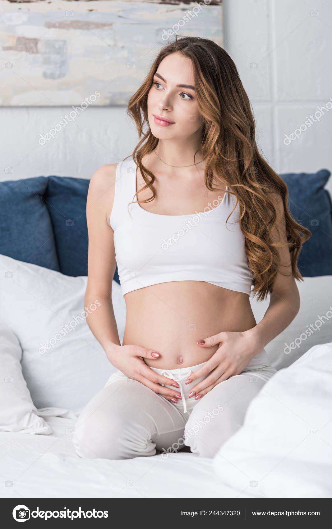 ベッドに座っておなかに触れて夢のような妊娠中の女性 — ストック写真 © AndrewLozovyi #244347320, image size:1068x1700