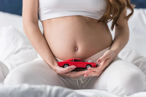 Vista Recortada Mujer Embarazada Sosteniendo Coche Juguete Rojo — Foto de Stock