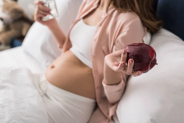 赤いリンゴを保持している妊娠中の女性の部分的なビュー — ストック写真