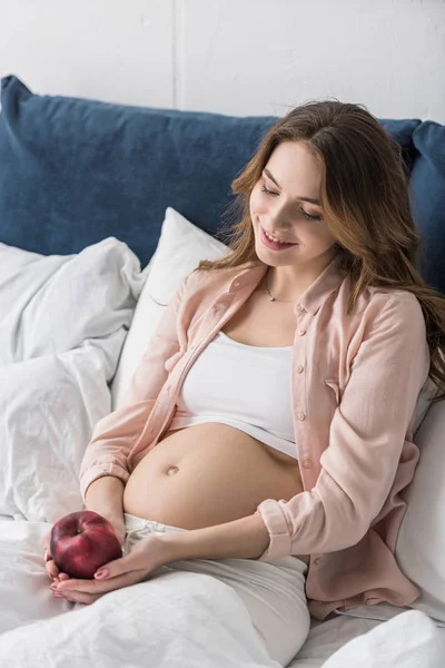 Sorrindo Mulher Grávida Deitada Cama Com Maçã Vermelha — Fotografia de Stock