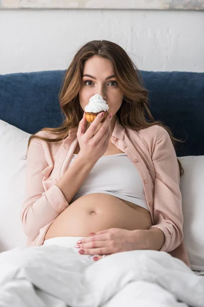 Atrakcyjna Kobieta Ciąży Leżenie Łóżku Jedzenie Babeczka — Zdjęcie stockowe