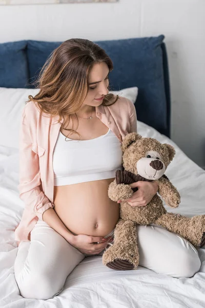 Jovem Grávida Sentada Cama Olhando Para Urso Brinquedo — Fotografia de Stock