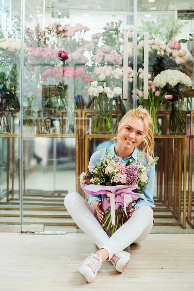 Hermosa Mujer Sonriente Sosteniendo Ramo Flores Mientras Está Sentado Frente — Foto de Stock