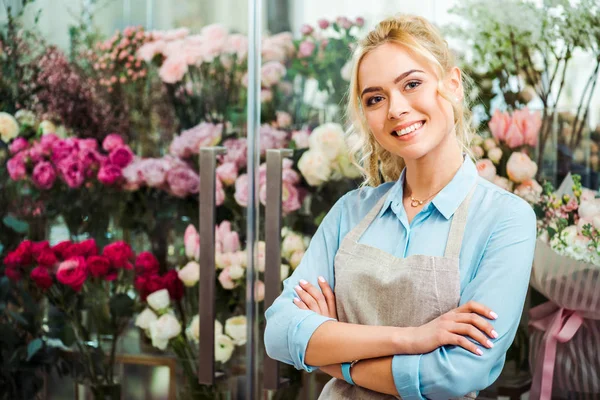 エプロンの背景にお花屋さんでカメラを見て美しい笑みを浮かべて女性花屋 — ストック写真