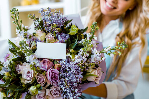 cropped view of woman and flower bouquet with roses, lilac and card with copy space