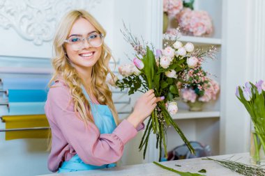 buket düzenlenmesi ve çiçekçi dükkanı kamerada bakarak gözlük güzel kadın çiçekçi