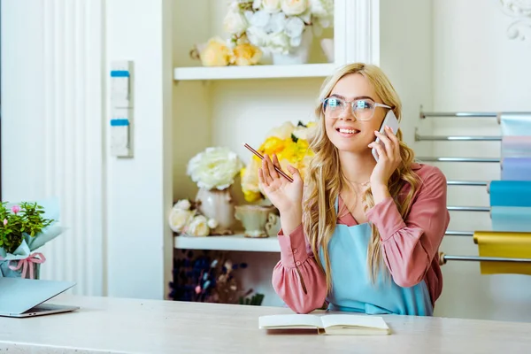 Mooie Vrouwelijke Bloem Winkeleigenaar Glazen Praten Smartphone Houden Van Potlood — Stockfoto