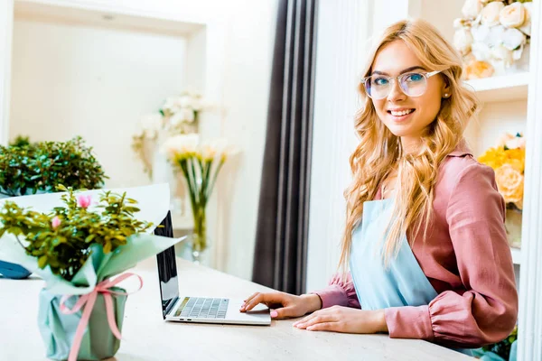 Hermosa Florista Femenina Gafas Usando Portátil Tienda Flores Mirando Cámara —  Fotos de Stock