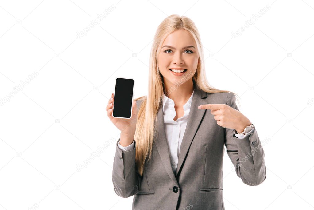 smiling businesswoman pointing at blank screen on smartphone, isolated on white
