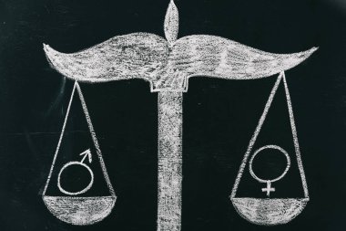 male and female signs on scales drawing on chalkboard, gender equality concept clipart