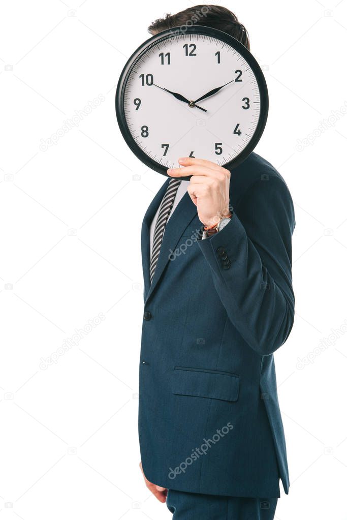 businessman holding clock in front of the face, isolated on white