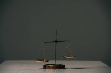 empty scales of justice on wooden table on grey  clipart
