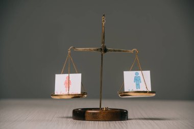 gri, cinsiyet eşitliği kavramı üzerinde ahşap masa üzerinde ölçekler üzerinde erkek ve kadın sembolleri