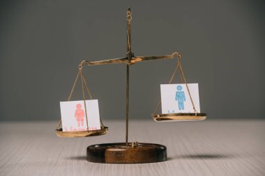 male and female signs on scales on wooden table, gender equality concept clipart